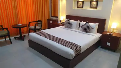 a hotel room with a bed and a table and chairs at Rouba Residency Hotel in Ponnāni