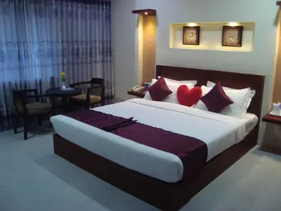 a bedroom with a large bed with red pillows at Rouba Residency Hotel in Ponnāni