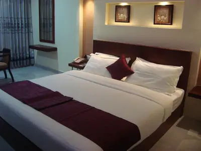 a bedroom with a large bed with white and red pillows at Rouba Residency Hotel in Ponnāni