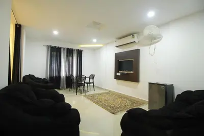 a living room with chairs and a tv on the wall at Half Moon Residency Calicut in Kozhikode