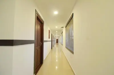 a hallway with white walls and a wooden door at Half Moon Residency Calicut in Kozhikode