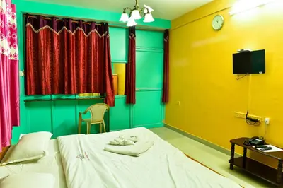 a room with a bed and a tv and curtains at RK Holiday Home in Ooty