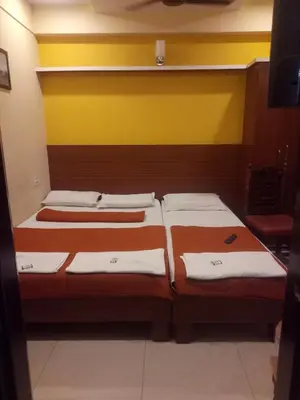 two beds in a room with yellow and yellow walls at hotel sangeeth lodging in Mysore