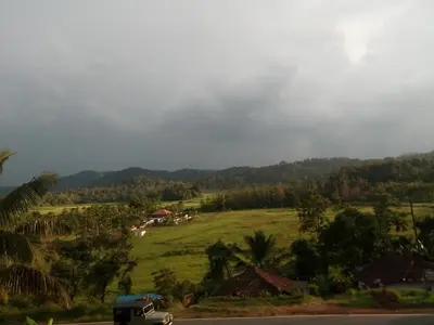 a truck driving down a road next to a field at Green Villa in Virajpet