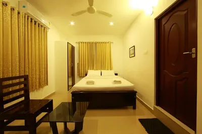 a bedroom with a bed and a chair and a window at Sara Hotels and Apartments in Nedumbassery