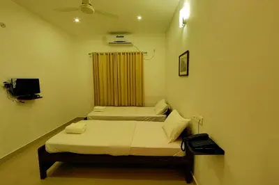 two beds in a small room with a window at Sara Hotels and Apartments in Nedumbassery