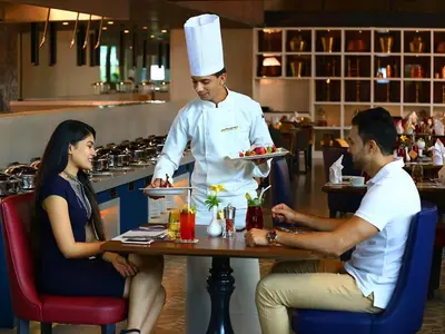 three people sitting at a table in a restaurant with a chef at Grand Mercure Mysore - An Accor Brand in Mysore