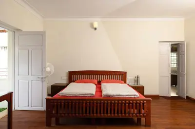 a bedroom with a bed with two red pillows on it at Colonels inn in Ooty