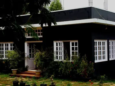 a black house with white windows and plants at The Black Magic Cottage in Ooty