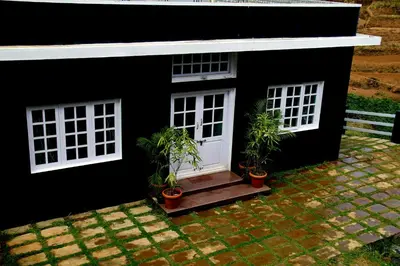 a black house with potted plants in front of it at The Black Magic Cottage in Ooty