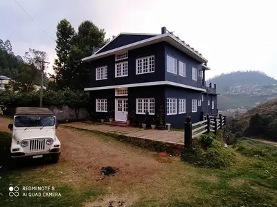 a blue house with a car parked in front of it at The Black Magic Cottage in Ooty