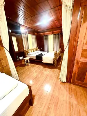 a bedroom with two beds and a wooden ceiling at Pugmarks Jungle Resort in Chekadi