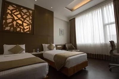 a hotel room with two beds and a window at Kiscol Grands Hotel in Coimbatore