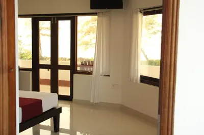 a bedroom with a bed and a view of a balcony at Petit Elephant in Cherai Beach