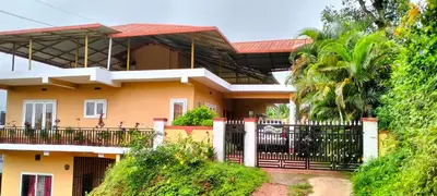 a yellow house with a black fence in front of it at Holidayincoorg Orchid Villa in Madikeri