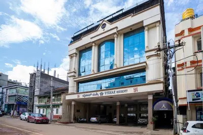 a building on a city street with cars parked at Hotel Vyshak residency in Mysore
