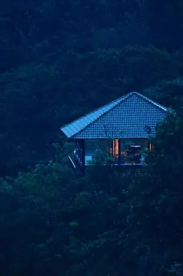 a house with a roof on top of a hill at The IBNII - Eco Luxury Resort in Madikeri