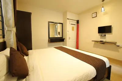 a hotel room with a bed and a tv at The Hill Side in Ooty