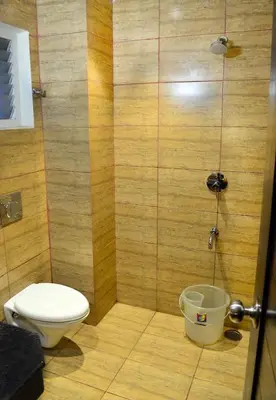 a bathroom with a toilet and a bucket at Ranis Grand in Coimbatore