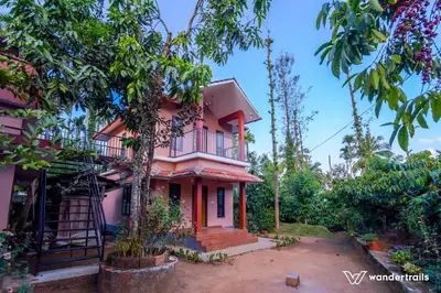 a pink house in the middle of trees at Sahyadri Homestay wayanad in Kalpetta
