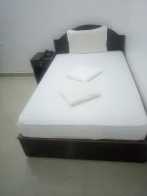 a bed with white sheets and two boxes on it at Ebenezer Plaza in Nedumbassery