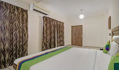 a bedroom with a large white bed and curtains at Treebo Komfort Suites, 3 Km From Mysore Palace in Mysore