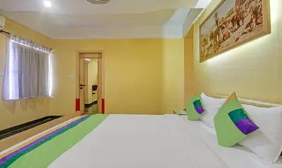 a bedroom with a large white bed with colorful pillows at Treebo Komfort Suites, 3 Km From Mysore Palace in Mysore