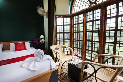 a bedroom with a bed and chairs and windows at LikeMyHome Homestay Mysore in Mysore