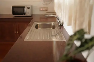 a kitchen counter with a sink and a microwave at Carpe DiemStay in Kushālnagar