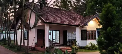 a small white house with a brown roof at Carpe DiemStay in Kushālnagar