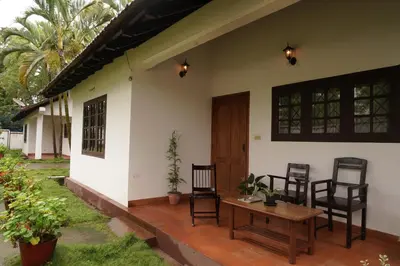 a porch of a house with chairs and a table at Carpe DiemStay in Kushālnagar