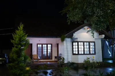 a small white house with windows at night at Carpe DiemStay in Kushālnagar