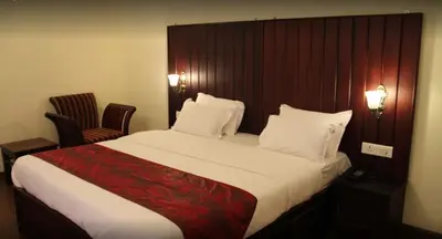 a bed in a hotel room with two chairs at Golden Springs in Ooty