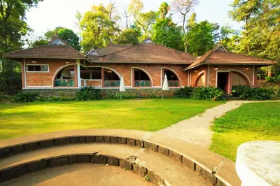 a house with a bridge in front of a yard at Misty Woods Resort in Kakkabe