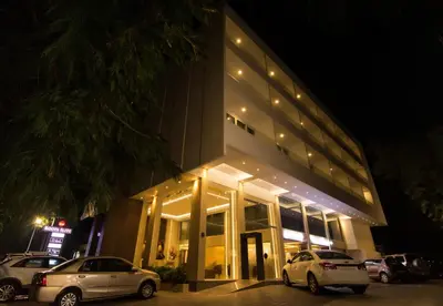 two cars parked in front of a building at night at Roopa Elite in Mysore