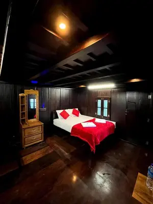 a bedroom with a large bed with a red blanket at NATURE CASTLE -Traditional villa,Vattavada in Kottakamboor