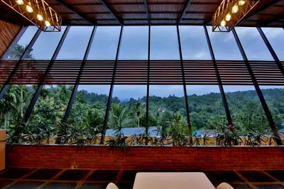 a room with a large window with plants at Le Villagio Resort & Domes in Sultan Bathery