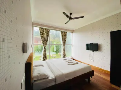 a bedroom with a bed and a large window at Tulips Valley View Resorts in Ooty
