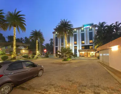 a car parked in front of a building with palm trees at Park Residency Koyilandi in Quilāndi