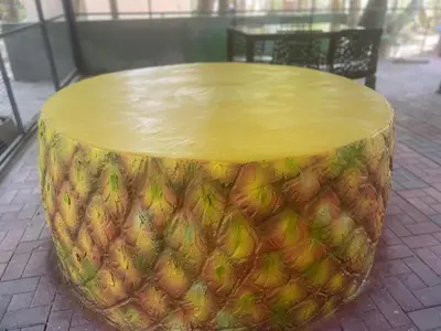 a wooden table with a pineapple sitting on a sidewalk at Greenwoods Nature Camp in Mudumalai National Park