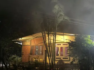a house with a palm tree in front of it at Greenwoods Nature Camp in Mudumalai National Park