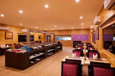a restaurant with tables and chairs and a bar at Sterling Anaikatti in Varagampadi