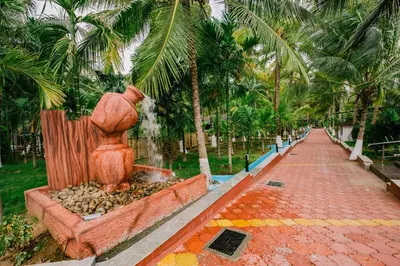 a statue of a woman sitting next to a palm tree at Sterling Anaikatti in Varagampadi