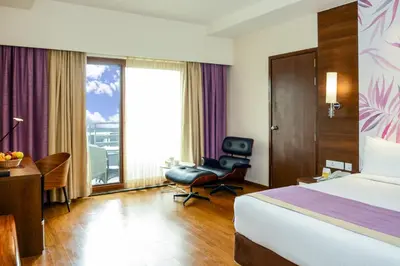 a hotel room with a bed and a desk and a chair at Purple Palms Resort & Spa in Kushālnagar