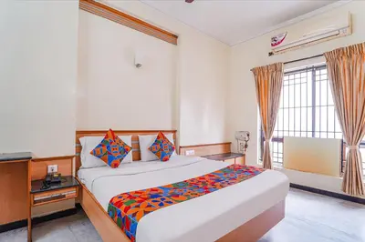 a bedroom with a bed and a desk and a window at FabHotel ESS Paradise in Coimbatore