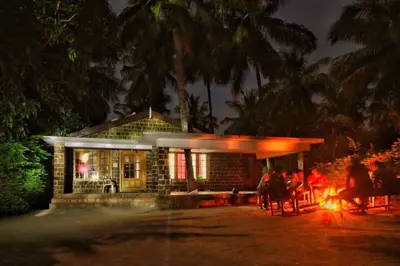 a house with a fire in front of it at night at Green Acres Farm Guest House in Masinagudi