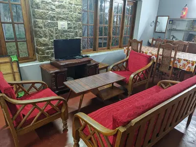 a room with chairs and a table and a tv at Green Acres Farm Guest House in Masinagudi