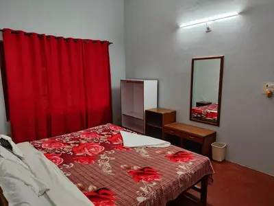 a bedroom with a bed with a red curtain at Green Acres Farm Guest House in Masinagudi