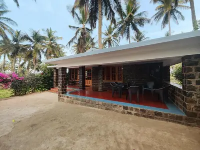 a house with palm trees in the background at Green Acres Farm Guest House in Masinagudi