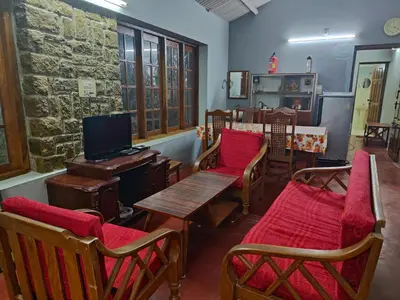 a room with chairs and a table and a tv at Green Acres Farm Guest House in Masinagudi